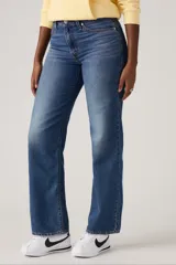 Jean azul de corte recto y tiro alto, con lavado medio y efecto desgastado en los muslos.