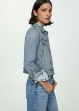 Chaqueta de jean celeste de corte clásico, con cuello camisero, cierre frontal con botones metálicos, bolsillos delanteros con solapa y puños abotonados.