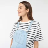 Enterito de jean celeste claro, estilo peto o jardinero, con panel elástico para maternidad sobre el abdomen. El corte de las piernas es recto y holgado.