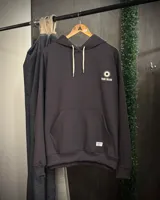 Canguro oversized color gris oscuro con capucha y estampado en la espalda que dice "TRIBU BRAND" y "THE JOURNEY CONTINUES SUMMER VOLUME II" junto a dos soles.