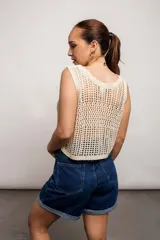 Blusa de tejido de punto calado color crema, sin mangas y corte crop.