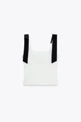 Top blanco de tejido elástico con escote cuadrado y tirantes con lazos decorativos. Tiene forro interior y cierre lateral con cremallera oculta.