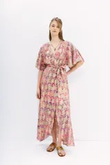 Vestido largo cruzado con estampado floral en tonos rosa, lila y dorado. Tiene mangas cortas amplias, escote en V y cintura elastizada con lazo.