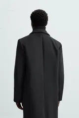 Abrigo negro regular fit confeccionado en paño con lana. Tiene cuello con solapas de muesca, manga larga, bolsillos de solapa en la cadera, bolsillo interior, abertura en el centro de la espalda y cierre frontal con botonadura.