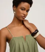 Mono de mujer color verde oliva, de pierna ancha y tiro alto, con escote recto y fruncidos en el busto. Los breteles son finos y trenzados en dos tonos.