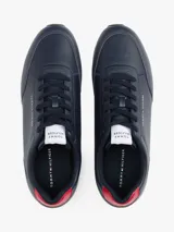 Zapatillas Tommy Hilfiger azul marino de corte bajo, con logo en el lateral y detalle rojo en el talón. Suela blanca dentada de goma.
