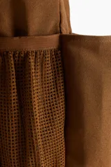 Bolso shopper marrón de lona de algodón con doble asa de mano y múltiples compartimentos exteriores, tres en los lados largos y uno de malla en los laterales.