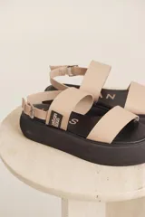Sandalias con plataforma color beige, con dos tiras anchas sobre el empeine y tira con hebilla alrededor del tobillo.