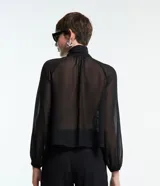 Blusa negra de chiffon con cuello alto con lazo, mangas largas con puños ajustados, detalle de volado delantero y volado en encaje.