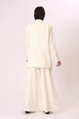 Pantalón palazzo color crudo con bordados florales en los laterales.