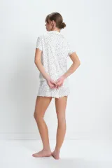 Conjunto de pijama corto de algodón blanco con estampado de pequeñas flores azules. Incluye camisa de manga corta con cuello y botones, y short con cintura elástica y volados en el ruedo.