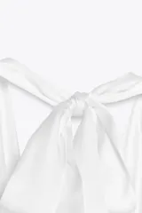 Top negro de satén con cuello halter drapeado ajustable con lazada en el cuello y espalda descubierta con lazada.