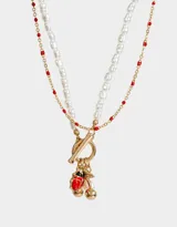 Set de dos collares dorados: uno de cadena con mostacillas rojas y otro de perlas con cierre marinero y dijes de vaquita de San Antonio, cerezas y perla.