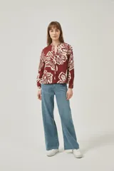 Camisa de poliéster con estampado floral en tonos borgoña y crema, corte holgado, cuello mao y cierre frontal con botones.