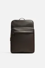 Mochila marrón de cuero sintético con textura grabada. Tiene un compartimento principal con cierre de cremallera, un bolsillo interno para dispositivos electrónicos de hasta 13 pulgadas y un bolsillo interno con cremallera. En la parte delantera tiene un bolsillo con cremallera. La parte posterior es acolchada y tiene una banda de sujeción para equipaje. Tiene un asa de mano y dos asas de hombro ajustables y acolchadas.