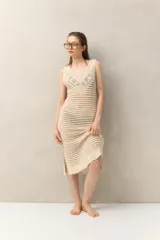 Vestido tejido a crochet color crema, de corte midi, sin mangas y con aberturas laterales.