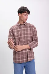 Camisa de cuadros en tonos marrones, de manga larga y cierre frontal con botones.