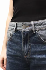 Pantalón de jean gris de corte recto y tiro medio, con bordado de estrella de ocho puntas en los bolsillos traseros.