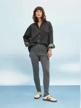 Camisa de denim negro con corte oversize, cuello clásico, cierre frontal con botones metálicos y bolsillo de parche en el pecho.