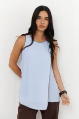 Musculosa color crudo con cuello redondo y ribete marrón en cuello, sisas y ruedo. Diseño cruzado en el frente y aberturas laterales.