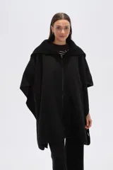 Poncho negro de tejido grueso, con cuello alto de punto acanalado y cierre frontal con cremallera.