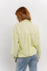 Camisa color crema de manga larga con cuello camisero y detalles de encaje en el escote. Se ata en la parte delantera.