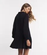 Vestido corto negro de viscosa con cuello en V, mangas largas abullonadas con lazo en los puños y falda con volantes.