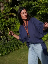 Collar con tira de cuero color suela y dije metálico dorado en forma de estribo.