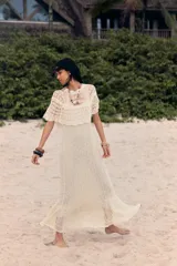 Vestido largo color crudo, tejido a crochet con diseño calado. Tiene cuello redondo, mangas cortas con volados y forro interior.
