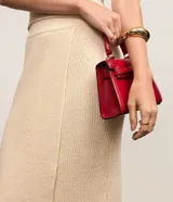 Pollera evasé midi de punto con cintura alta y elástico. Presenta un diseño con traspase delantero.