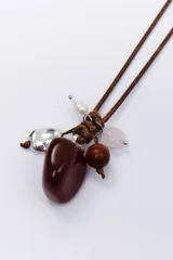 Colgante con cordón marrón ajustable y dije de piedra beige con manchas negras, cuentas de madera marrón, piedra blanca opaca y dije plateado en forma de pluma.