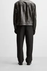 Pantalón negro de corte recto con cintura elástica, bolsillos delanteros y traseros. Cierre frontal con cremallera y botón.