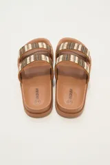 Sandalias tipo slide de plataforma color marrón, con dos tiras anchas sobre el empeine decoradas con tejido de rafia en tonos marrón, negro y beige.