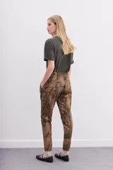 Pantalón babucha de tiro medio, ajustado en tobillos, con estampado de piel de serpiente en tonos marrones y negros. Posee bolsillos diagonales y cintura elastizada con cordón de ajuste.