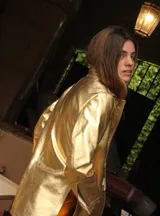 Blazer de cuero color fucsia con aberturas laterales y aplique tipo pin desplegable bañado en bronce, complementado con botones de nácar.