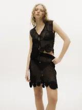 Conjunto de top y falda tejidos a crochet color rojo. El top es tipo chaleco con ajuste frontal con cordones y la falda es corta con pretina elástica y apliques de flores en el ruedo.