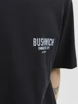 Remera negra de manga corta y cuello redondo, con fit relajado y estampado frontal con la palabra "BUSHWICH" y el texto "EMBRACE THE CITY". Confeccionada en punto single jersey orgánico.