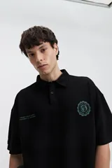Polo azul marino con textura y corte oversize. Presenta un logo estampado en el pecho y mangas cortas.