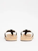 Ojotas Tommy Hilfiger con plantilla de corcho natural, base color beige y tiras acolchadas con el logo de la marca en blanco, marrón y negro.