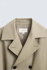 Trench largo regular fit color beige confeccionado en tejido italiano repelente al agua. Tiene cuello con solapas de pico, manga larga con puño ajustable con trabilla, bolsillos de vivo en cadera, bolsillo interior, cinturón del mismo tejido en cintura, bajo con abertura en centro espalda y cierre frontal de botonadura cruzada.