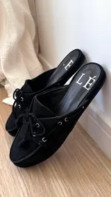 Mules de cuero gamuzado color negro, con detalle de cordones y ojales metálicos.