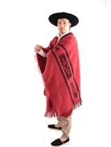 Poncho rojo con guarda pampa negra en los bordes y flecos.