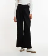 Pantalón largo negro de material sintético con cintura elástica, bolsillos laterales tipo cargo y abotonado delantero.
