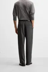 Pantalón relaxed fit color verde oscuro, con pliegues en la parte delantera, bolsillos laterales y traseros de ojal. Cierre frontal con cremallera y botón.