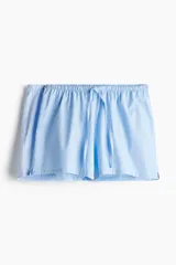 Shorts de pijama celestes con cintura elástica y cordón ajustable. Uno de los lados es de tela a rayas verticales blancas y celestes.
