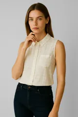 Blusa sin mangas color crema con estampado a cuadros, cuello camisero, cierre frontal con botones y bolsillo de parche en el pecho.