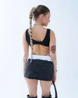 Minifalda de jean negro con cintura irregular y ruedo desflecado.