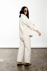 Pantalón wide leg de lino y algodón color crudo con rayas verticales finas color rosa. Tiene tiro medio, cartera cruzada con botones carey y bolsillos laterales.