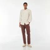 Camisa de lino color beige claro, de corte regular, con cuello clásico y mangas largas con puños abotonados.