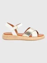 Sandalia con tiras cruzadas doradas con textura de piel de serpiente y ajuste con hebilla en el tobillo. Base tejida tipo esparto y plantilla acolchada.